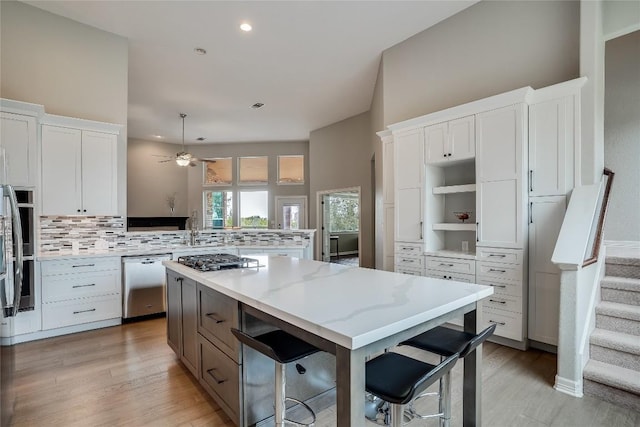 kitchen with appliances with stainless steel finishes, backsplash, white cabinetry, and a peninsula