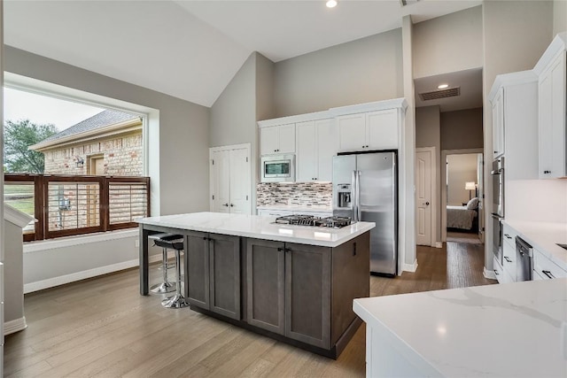 kitchen with appliances with stainless steel finishes, white cabinetry, visible vents, and a center island