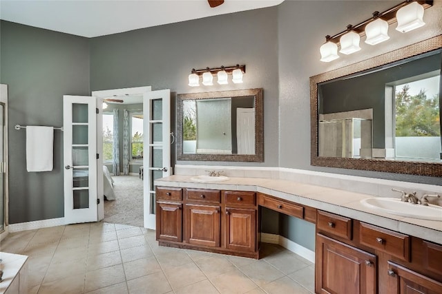 full bathroom featuring double vanity, a stall shower, a sink, and french doors