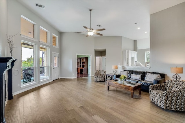 living room featuring baseboards, a high ceiling, visible vents, and wood finished floors