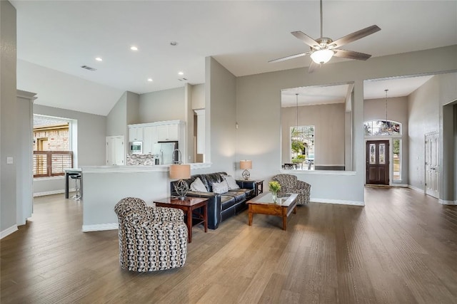 living room with high vaulted ceiling, wood finished floors, visible vents, and baseboards