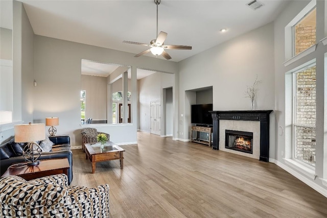 living room featuring visible vents, a ceiling fan, wood finished floors, a tile fireplace, and baseboards