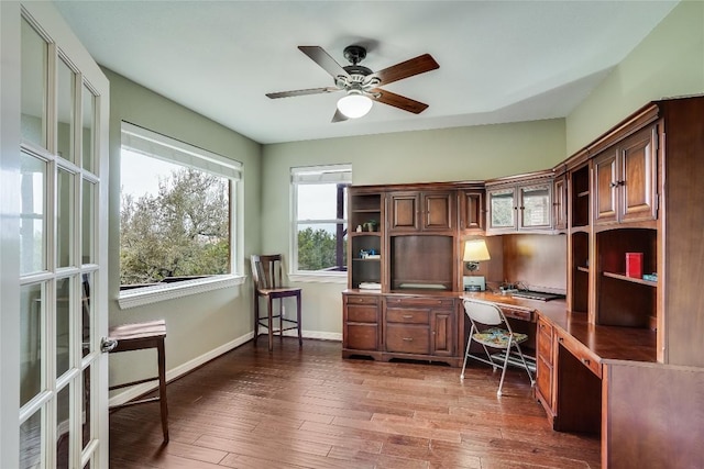 office area with ceiling fan, hardwood / wood-style floors, built in desk, and baseboards