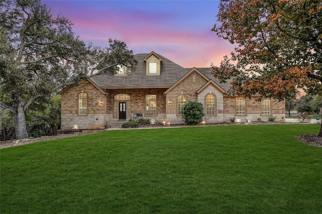 french provincial home with roof with shingles and a yard