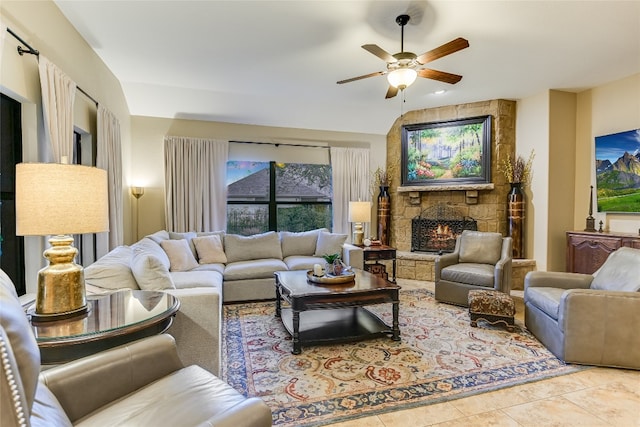 living area featuring a stone fireplace, tile patterned flooring, and a ceiling fan