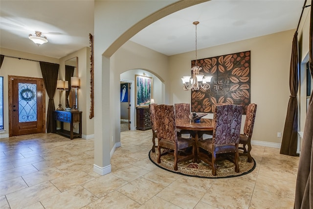 dining room with arched walkways, baseboards, and a notable chandelier