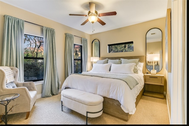 bedroom with a ceiling fan, light carpet, and baseboards