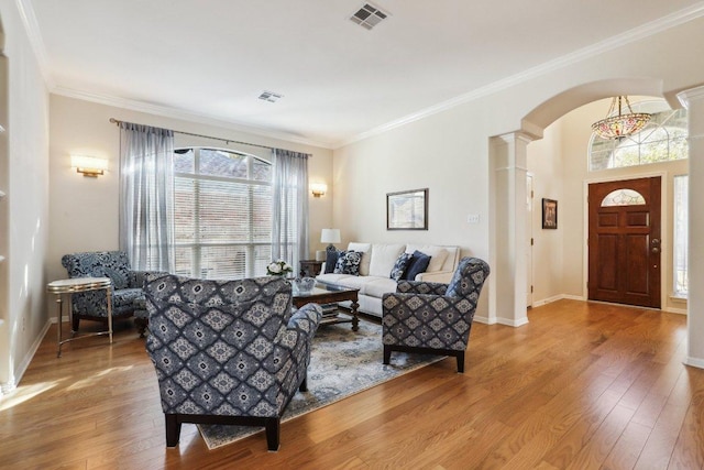 living area with arched walkways, decorative columns, wood finished floors, and visible vents