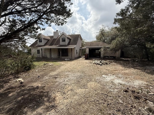 view of front of house featuring brick siding, driveway, and a chimney