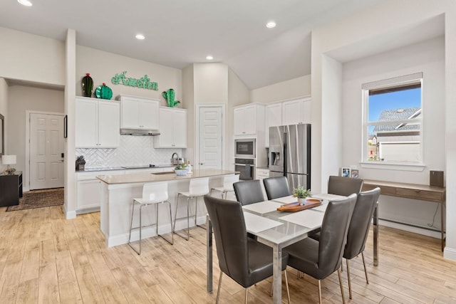 dining room featuring light wood-style floors, recessed lighting, and vaulted ceiling