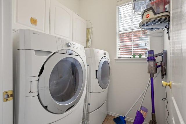 washroom with cabinet space, light tile patterned floors, and washing machine and clothes dryer