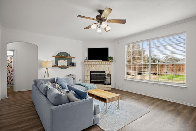 living room featuring a fireplace, arched walkways, wood finished floors, and ornamental molding