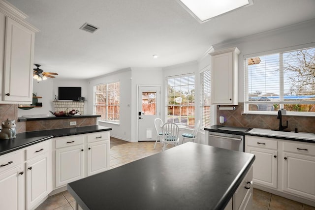 kitchen featuring a sink, dark countertops, backsplash, and dishwasher