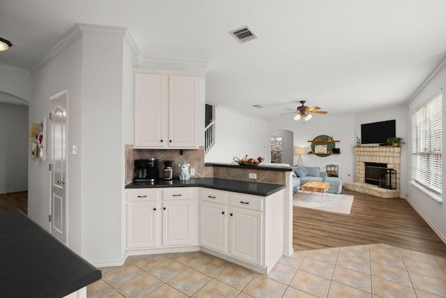 kitchen featuring visible vents, arched walkways, dark countertops, a peninsula, and light tile patterned flooring