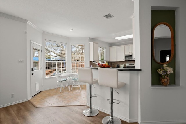 kitchen with visible vents, dark countertops, appliances with stainless steel finishes, white cabinetry, and backsplash