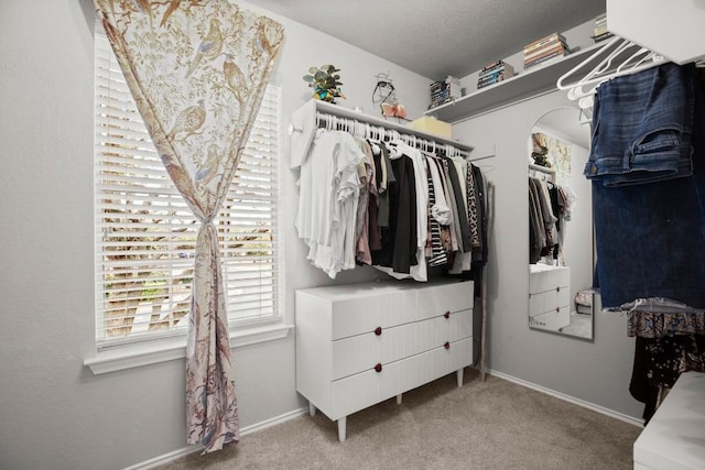 spacious closet with arched walkways and carpet flooring