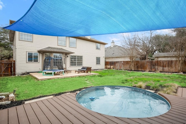 rear view of property featuring a deck, a yard, a fenced backyard, and a hot tub