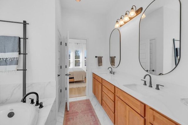 full bath featuring marble finish floor, double vanity, a sink, and a bath