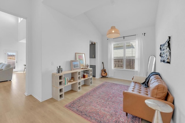 sitting room with light wood-type flooring and high vaulted ceiling