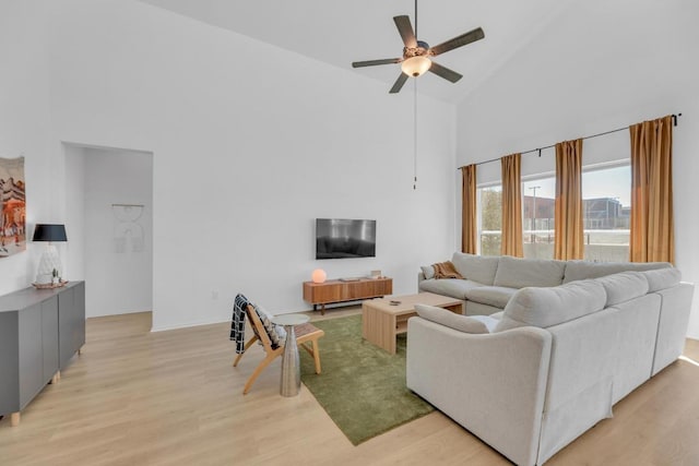 living area featuring high vaulted ceiling, a ceiling fan, and light wood-style floors