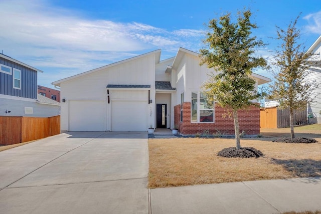 view of front of property with a garage, concrete driveway, brick siding, and fence