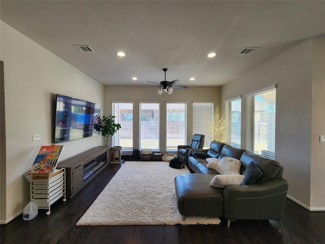 living room featuring visible vents, a healthy amount of sunlight, and dark wood-style flooring