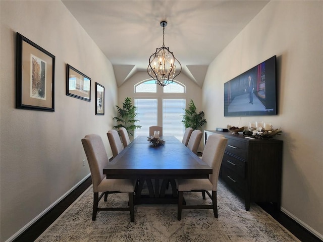 dining space featuring vaulted ceiling, wood finished floors, baseboards, and a chandelier