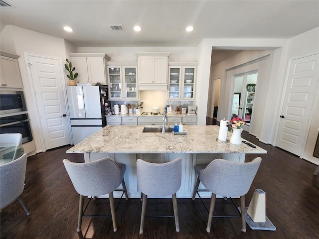 kitchen featuring a breakfast bar area, white cabinets, visible vents, and appliances with stainless steel finishes