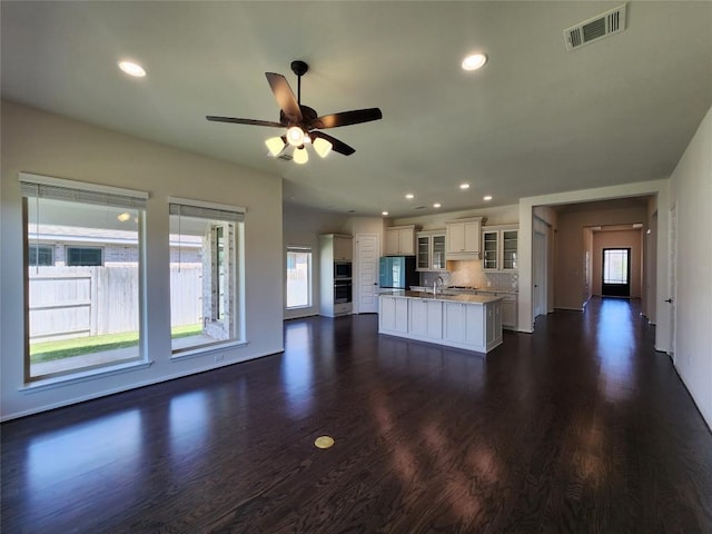 522 Jefferson Dr, Kyle, TX 78640 - kitchen featuring appliances with stainless steel finishes, a center island with sink, dark wood-style floors, white cabinetry, and a ceiling fan