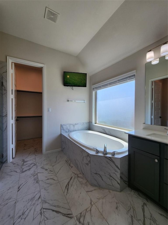 522 Jefferson Dr, Kyle, TX 78640 - bathroom featuring marble look tiles, vanity, a bath, vaulted ceiling, and a shower