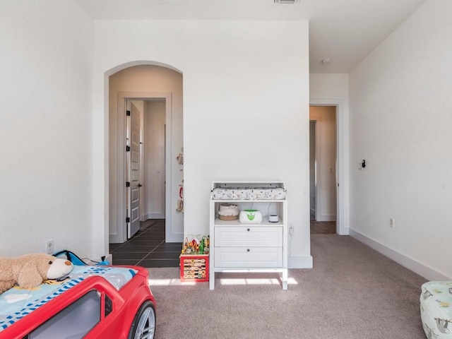 carpeted bedroom with arched walkways, visible vents, and baseboards