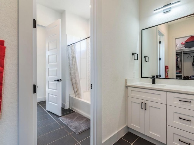 full bath featuring a walk in closet, shower / bath combo with shower curtain, vanity, baseboards, and tile patterned floors