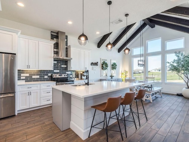 kitchen featuring visible vents, wall chimney exhaust hood, appliances with stainless steel finishes, a sink, and backsplash