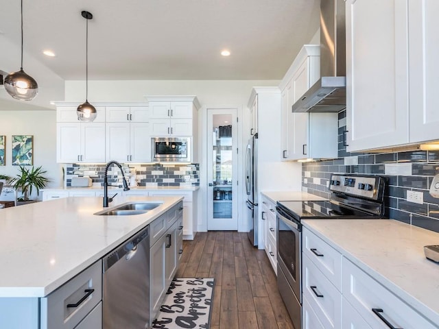 kitchen with appliances with stainless steel finishes, white cabinetry, a sink, and wall chimney exhaust hood