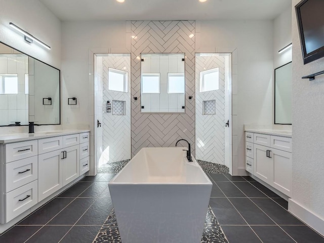 bathroom with a sink, two vanities, a freestanding tub, and tile patterned floors