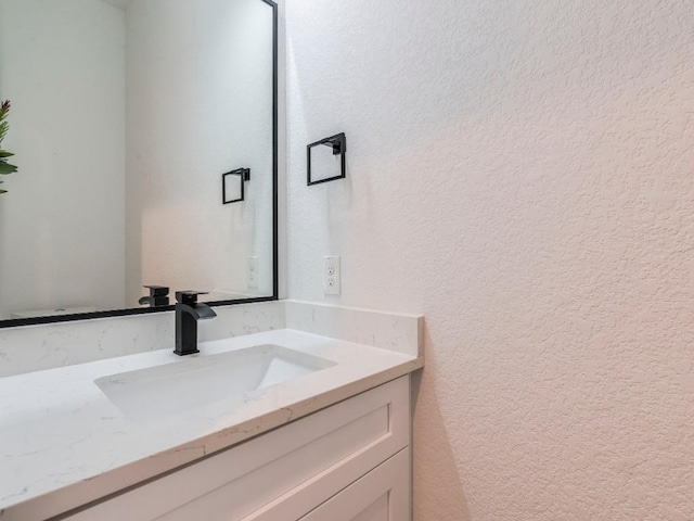 bathroom featuring a textured wall and vanity