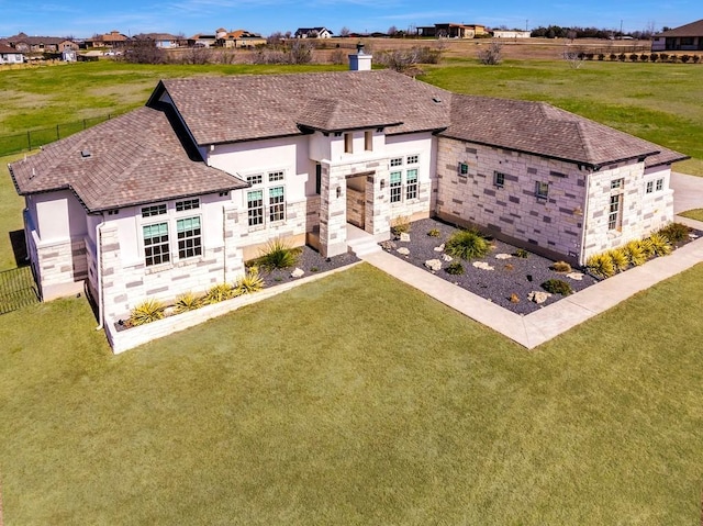 rear view of house featuring stone siding, a chimney, a lawn, and stucco siding