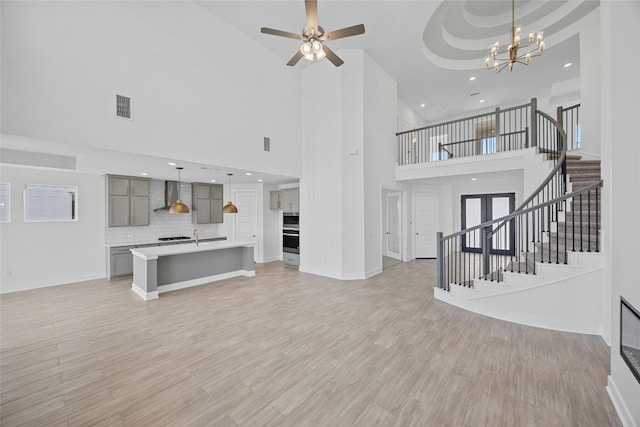 216 Echo Pass, Liberty Hill, TX 78642 - unfurnished living room featuring a towering ceiling, stairway, recessed lighting, a chandelier, and light wood-style floors