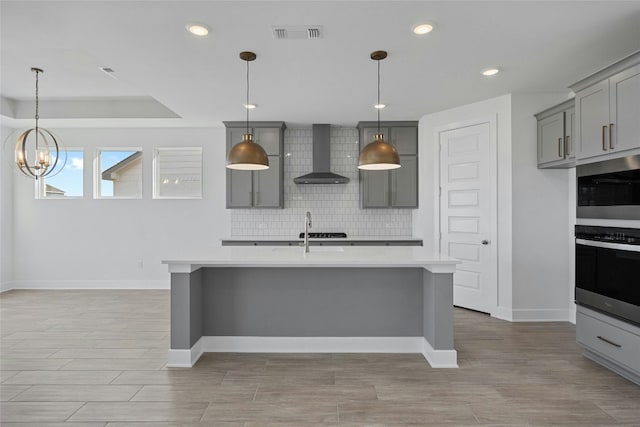 216 Echo Pass, Liberty Hill, TX 78642 - kitchen with wall chimney exhaust hood, stainless steel appliances, gray cabinetry, light countertops, and backsplash