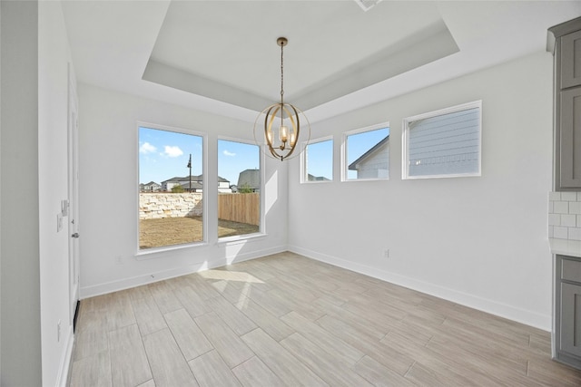 216 Echo Pass, Liberty Hill, TX 78642 - unfurnished dining area featuring a raised ceiling, a chandelier, and light wood-type flooring