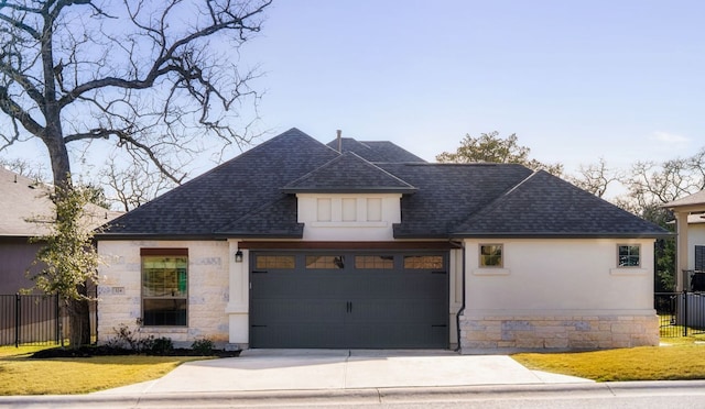 view of front facade featuring driveway, stone siding, a shingled roof, and fence