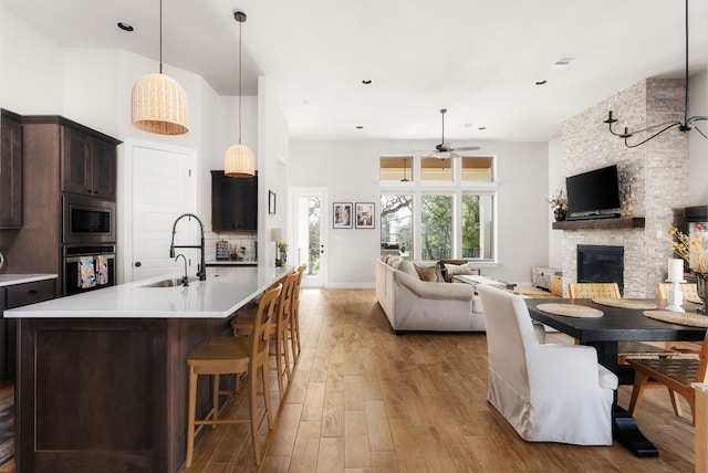 kitchen featuring stainless steel appliances, open floor plan, a sink, and dark brown cabinets