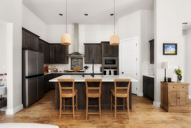 kitchen with dark brown cabinetry, wall chimney exhaust hood, stainless steel appliances, and light countertops