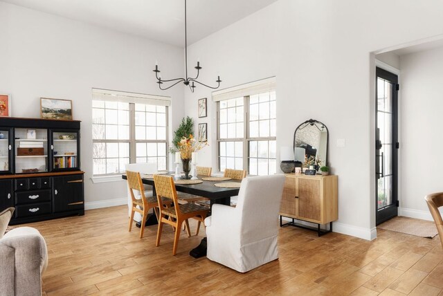 dining area with a chandelier, light wood-style flooring, and baseboards