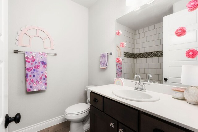 bathroom with walk in shower, vanity, toilet, and baseboards