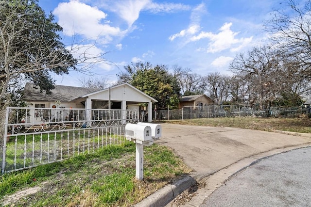 view of front of property featuring a fenced front yard, concrete driveway, and a carport