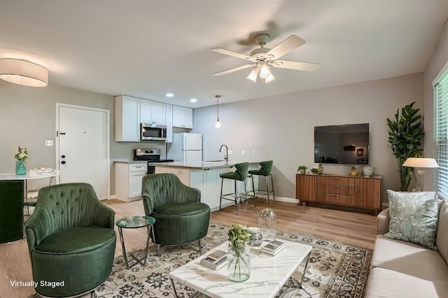 living room featuring ceiling fan, recessed lighting, baseboards, and light wood-style floors