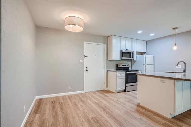 kitchen featuring stainless steel appliances, a sink, white cabinetry, baseboards, and light wood-type flooring