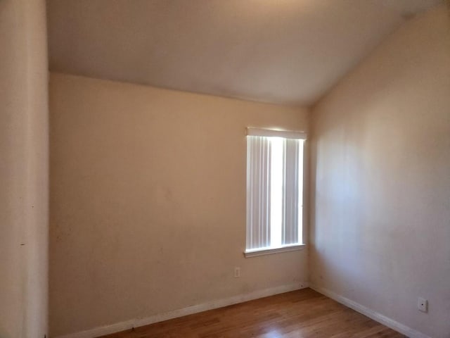 empty room with lofted ceiling, baseboards, and wood finished floors