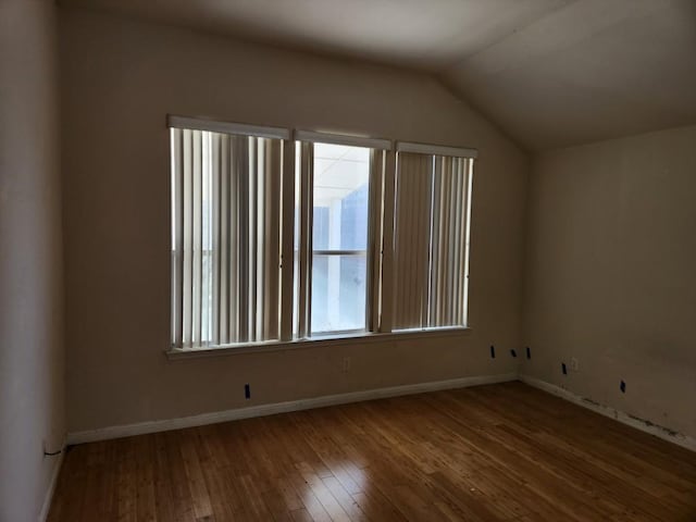 empty room with vaulted ceiling, hardwood / wood-style flooring, and baseboards